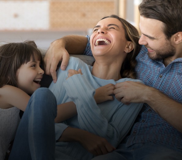 Family of three laughing together on couch