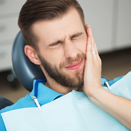 Man in need of root canal therapy holding jaw in pain