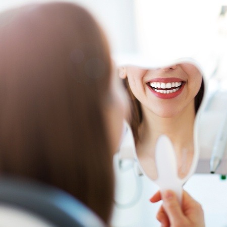 Woman looking in mirror after smile makeover