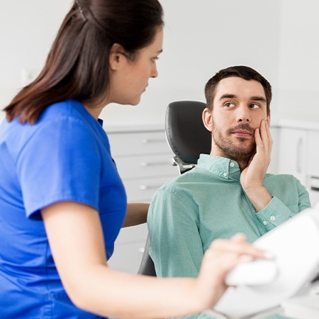 Man holding cheek during dental emergency visit
