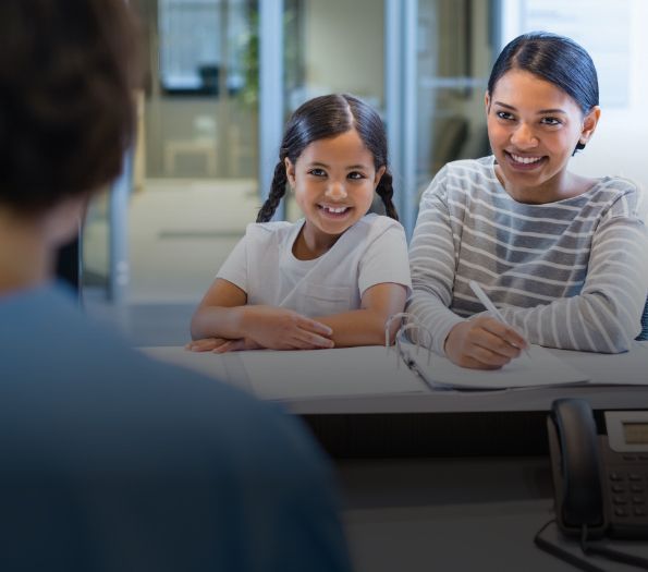 Mother and daughter checking in at dental office reception desk