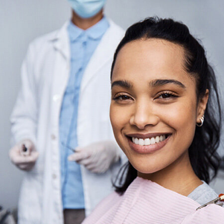 smiling woman in the chari with the dentist standing nearby