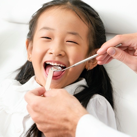 Dentist checking child's smile during her first visit