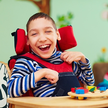 Little boy in wheelchair laughing after special needs children's dentistry