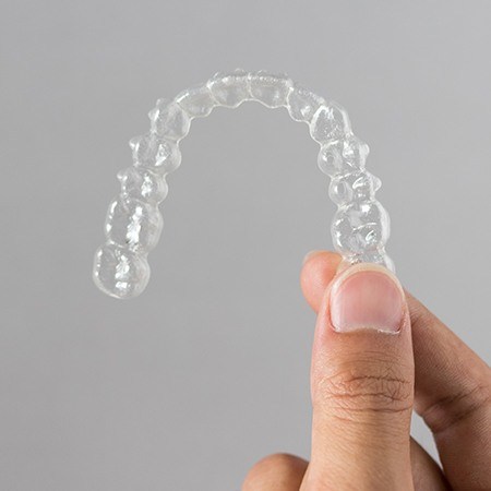 Hand holding an Invisalign tray