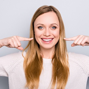 young woman pointing to her smile