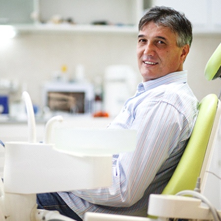 Senior man sitting in a chair wearing dentures in Fresno, CA