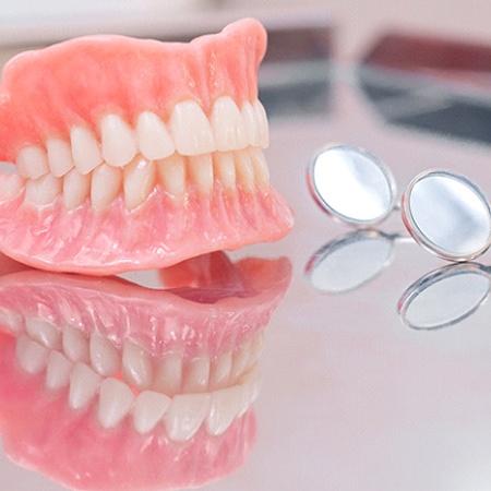 Dentures in Fresno, CA, on glass table with dental mirror