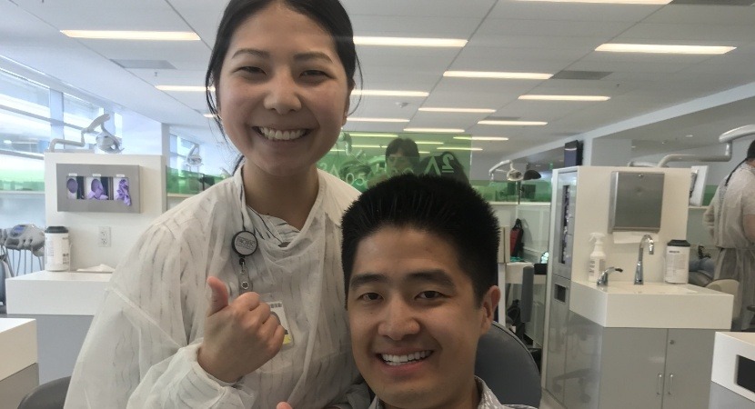 Dentist standing next to smiling dental patient in exam chair