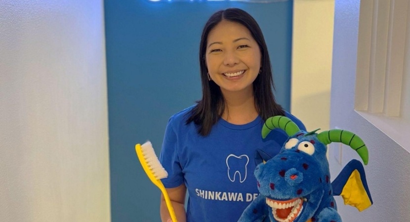 Dentist standing next to smiling dental patient in exam chair