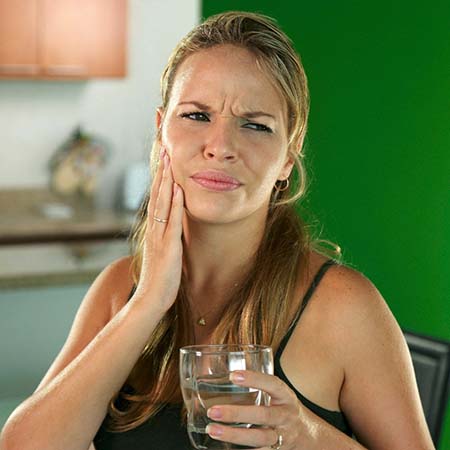 Woman with a dental emergency in Fresno holding water