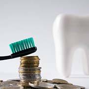 Toothbrush resting on stack of coins next to model tooth