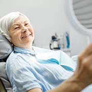 Older woman smiling in dental mirror at the dental office