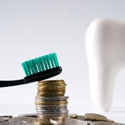Toothbrush resting on a stack of change next to a tooth