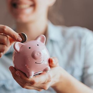 Woman putting a coin into her piggy bank