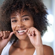 woman smiling while flossing