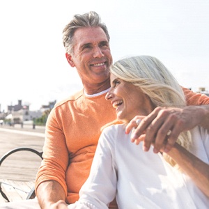 Older couple with dental implants in Fresno smiling and hugging