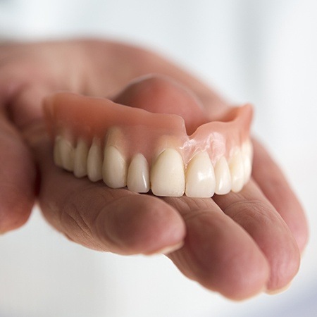 Hand holding a full denture