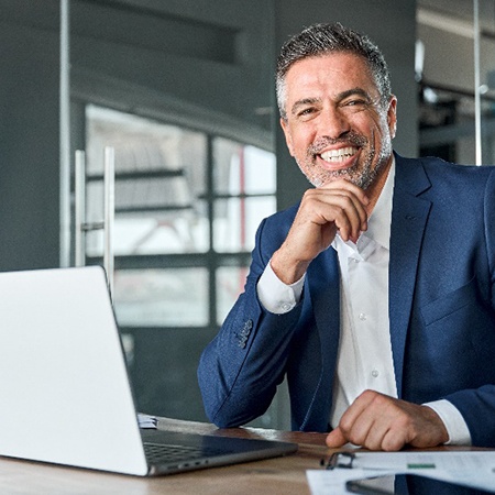 Man in blue suit smiling while working on computer in office