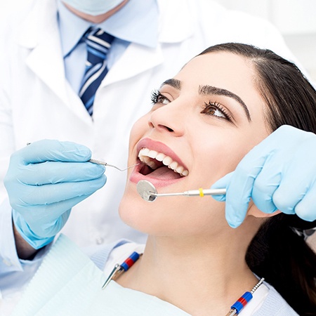 woman smiling while dentist is looking in mouth 