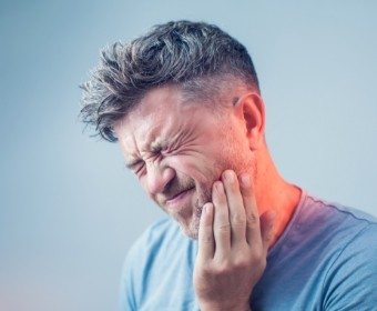 Man in need of emergency dentistry holding jaw in pain