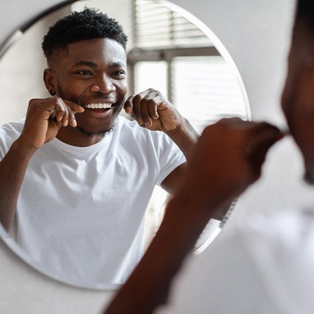 Patient with white teeth smiling while flossing