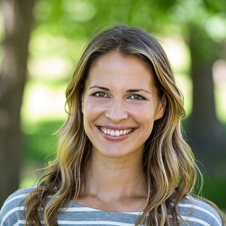 Woman in striped shirt smiling in park