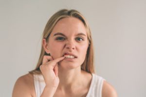 Woman with a toothache touching her tooth with her finger