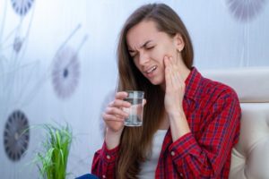 Woman with sensitive teeth in pain after drinking cold water