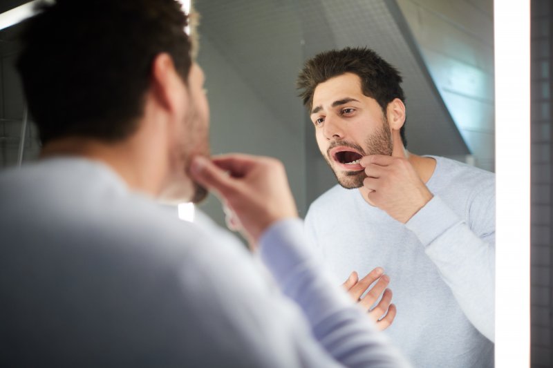 Closeup of man looking at tooth in mirror