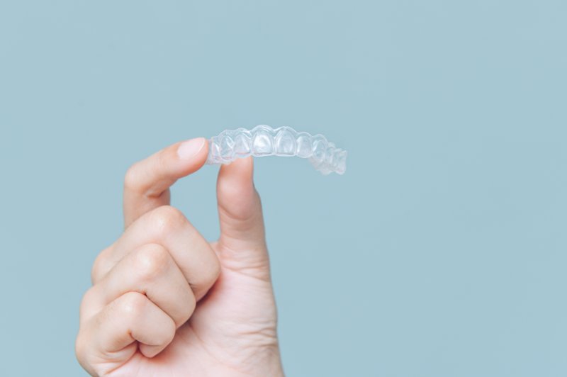 Patient holding up Invisalign aligner