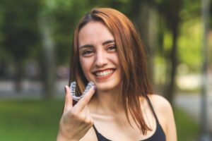 Woman holding Invisalign clear aligner.