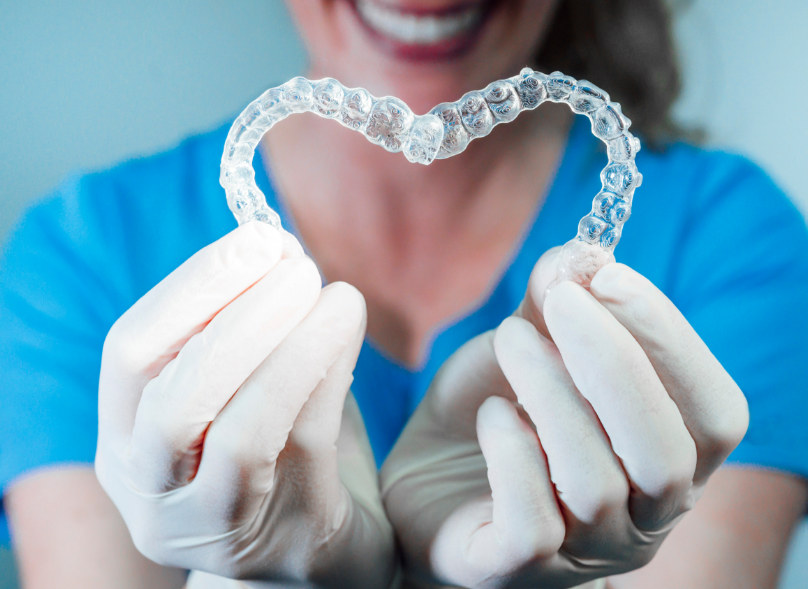 Dentist holding two retainers in a heart shape