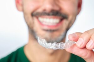Man holding up his Invisalign tray