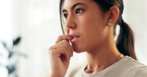 Woman looking worried biting her fingernail.
